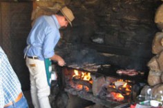 A man cooking over an open flame barbeque.